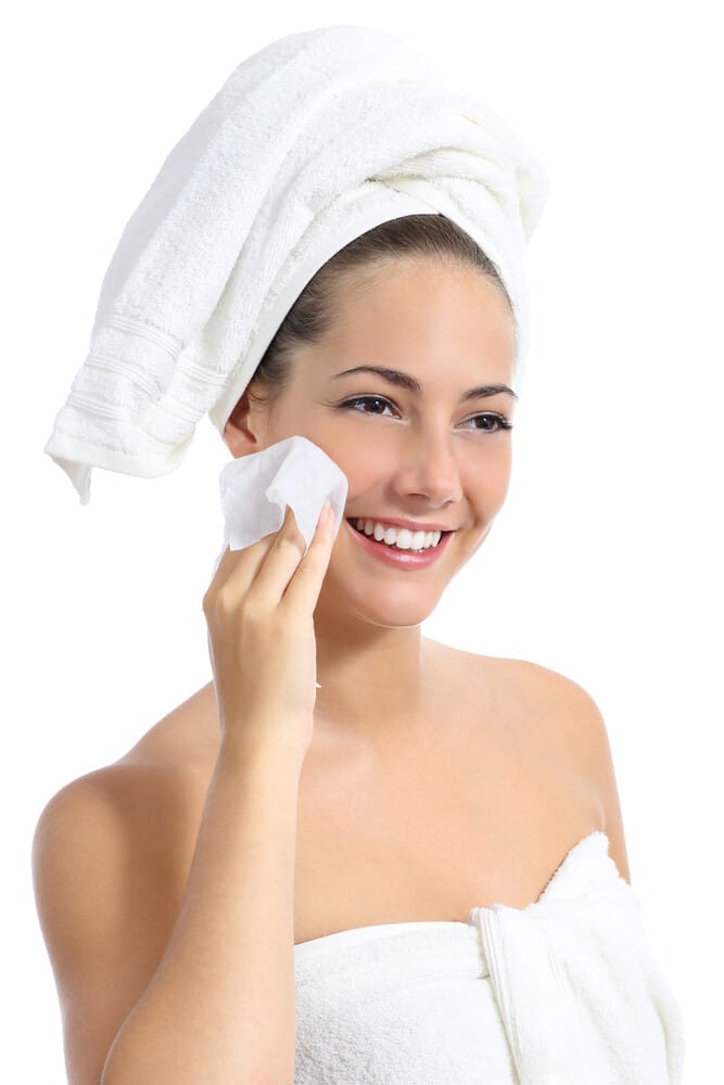 Beautiful woman cleaning her face with a baby wipe isolated on a white background