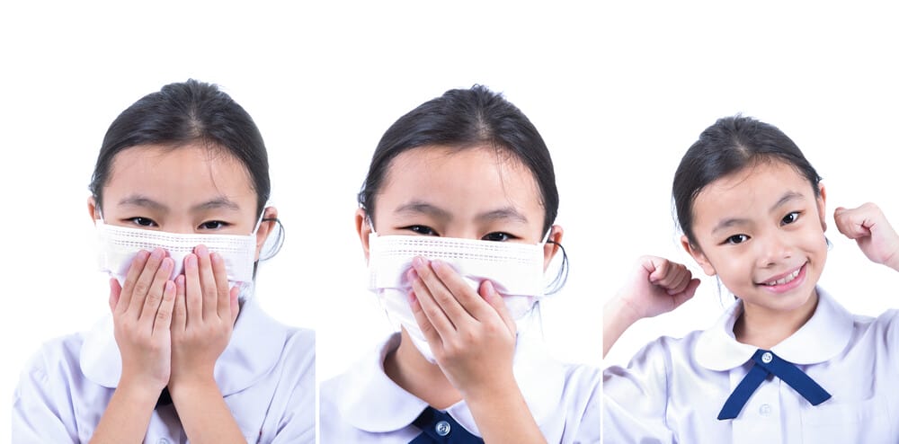 Common cold little asia girl with facemask in white isolated background